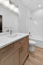 Full bathroom featuring light wood-style flooring, vanity, shower / bath combination, and recessed lighting