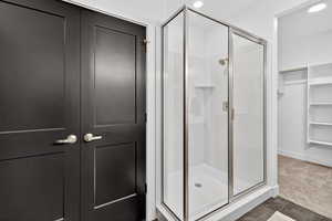 Bathroom with a shower stall, recessed lighting, and a walk in closet