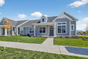 View of front facade featuring board and batten siding, a front lawn, covered porch, and roof with shingles