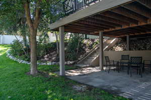 View of grassy yard featuring stairs, a patio, and a deck