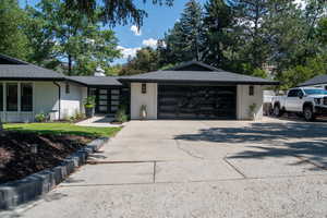 View of side of home with brick siding, concrete driveway, a chimney, and a shingled roof