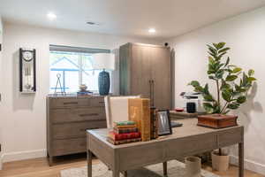 Office with light wood-style floors and recessed lighting