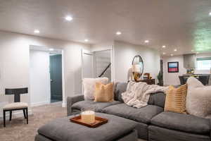 Living area with a textured ceiling, carpet, and recessed lighting