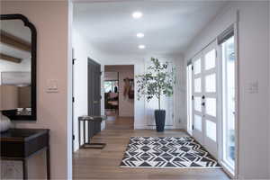 Foyer featuring light wood-type flooring, ornamental molding, french doors, and recessed lighting