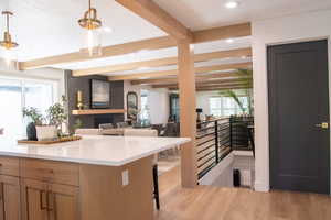 Kitchen with a breakfast bar area, light wood-type flooring, decorative light fixtures, beamed ceiling, and recessed lighting