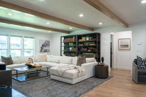 Living room with recessed lighting, beam ceiling, and light wood-style flooring