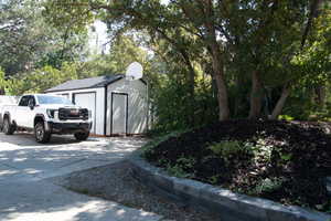 View of shed featuring a garage and view of scattered trees