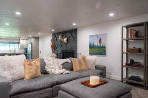 Living area with carpet, a textured ceiling, a fireplace, and recessed lighting