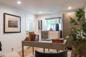 Office area with light wood finished floors and recessed lighting