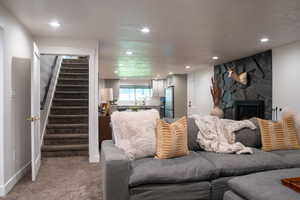Carpeted living area with stairway, a fireplace, recessed lighting, and a textured ceiling