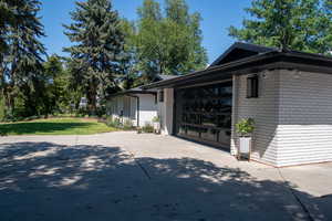 View of home's exterior featuring brick siding, driveway, a lawn, and an attached garage