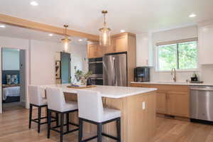 Kitchen with stainless steel appliances, light wood-type flooring, a center island, tasteful backsplash, and recessed lighting