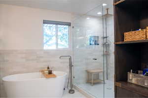 Full bath with a freestanding tub, tile walls, a shower stall, and a wainscoted wall