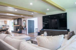 Living room with beamed ceiling, recessed lighting, wood finished floors, and a fireplace