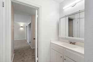 Bathroom with vanity and light colored carpet