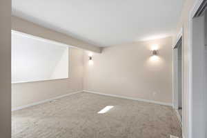 Carpeted spare room featuring baseboards