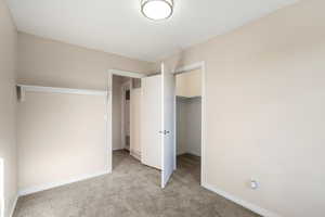 Unfurnished bedroom with a spacious closet and light carpet