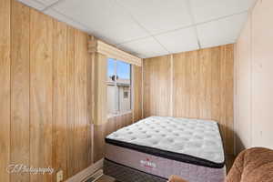 Bedroom with a paneled ceiling and wooden walls
