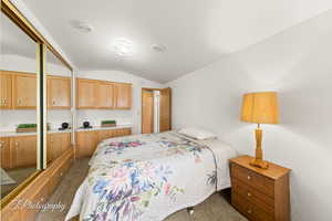 Carpeted bedroom with vaulted ceiling and a closet