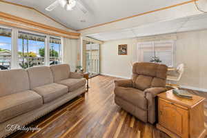Living room with healthy amount of natural light, hardwood / wood-style flooring, lofted ceiling, a ceiling fan, and crown molding