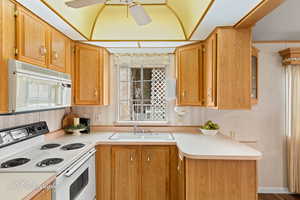 Kitchen with white appliances, light countertops, wallpapered walls, glass insert cabinets, and ceiling fan