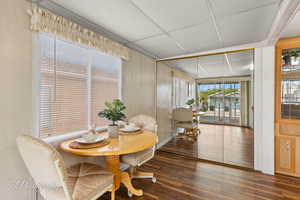 Dining space with dark wood-type flooring and a drop ceiling