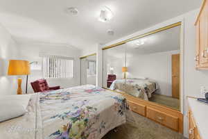Bedroom with carpet flooring, lofted ceiling, and two closets