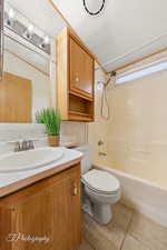 Bathroom with wallpapered walls, shower / bath combination, vanity, and light tile patterned flooring