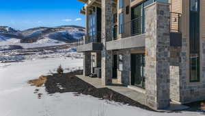 Snow covered property entrance featuring stone siding and a mountain view