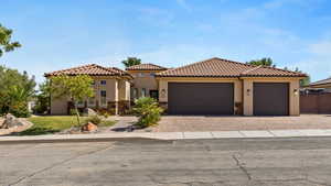 Mediterranean / spanish-style home featuring stucco siding, decorative driveway, and stone siding