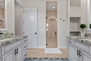 Bathroom with a stall shower, two vanities, light tile patterned floors, and recessed lighting