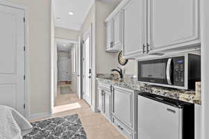 Kitchen with light stone countertops, refrigerator, stainless steel microwave, recessed lighting, and light tile patterned flooring