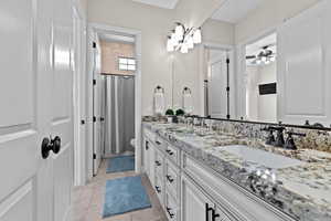 Bathroom featuring double vanity, light tile patterned floors, and curtained shower