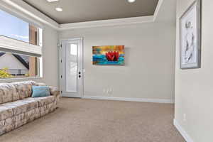 Carpeted living area featuring a raised ceiling and recessed lighting