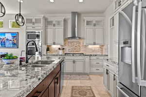 Kitchen featuring stainless steel appliances, glass insert cabinets, decorative backsplash, light stone counters, and recessed lighting