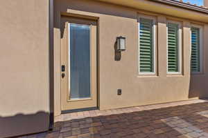 Entrance to property with stucco siding and a patio area