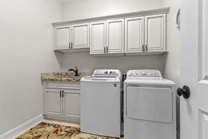 Washroom with cabinet space, washing machine and clothes dryer, and light tile patterned floors