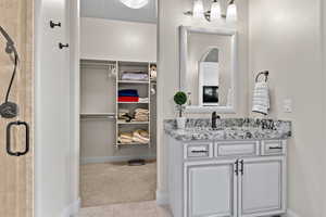 Bathroom with a stall shower, a walk in closet, vanity, and light tile patterned flooring