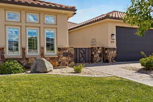 Exterior space featuring stucco siding, a tile roof, stone siding, a yard, and driveway