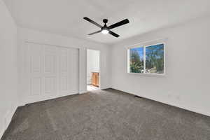 Unfurnished bedroom featuring carpet floors, ensuite bath, a closet, and ceiling fan