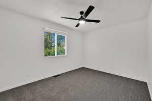 Empty room with carpet, a textured ceiling, and ceiling fan