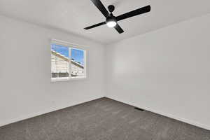 Carpeted empty room with a textured ceiling and ceiling fan