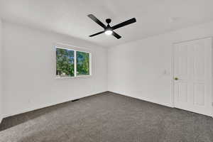 Unfurnished bedroom featuring carpet floors, ensuite bath, a closet, and ceiling fan