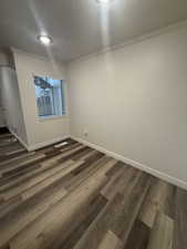 Empty room featuring a textured ceiling, dark wood-style floors, and crown molding