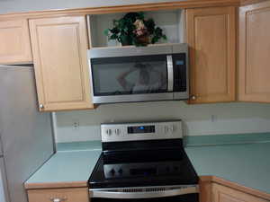 Kitchen with appliances with stainless steel finishes, light countertops, and light brown cabinetry