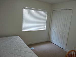 Bedroom featuring light carpet and a closet
