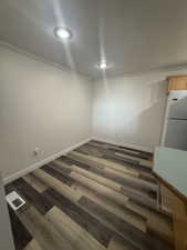 Unfurnished dining area featuring ornamental molding, a textured ceiling, and dark wood-type flooring