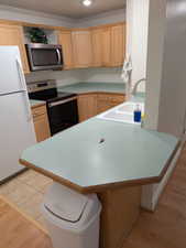 Kitchen featuring a breakfast bar, light countertops, appliances with stainless steel finishes, crown molding, and open shelves