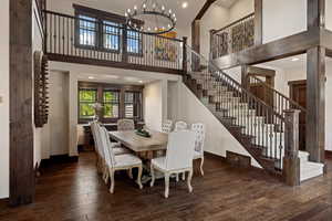Dining room with recessed lighting, dark wood-type flooring, a towering ceiling, a chandelier, and stairway