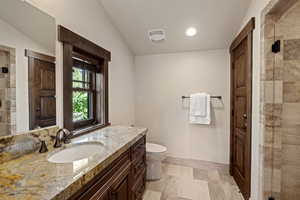 Bathroom featuring vanity, a shower stall, recessed lighting, stone tile floors, and lofted ceiling